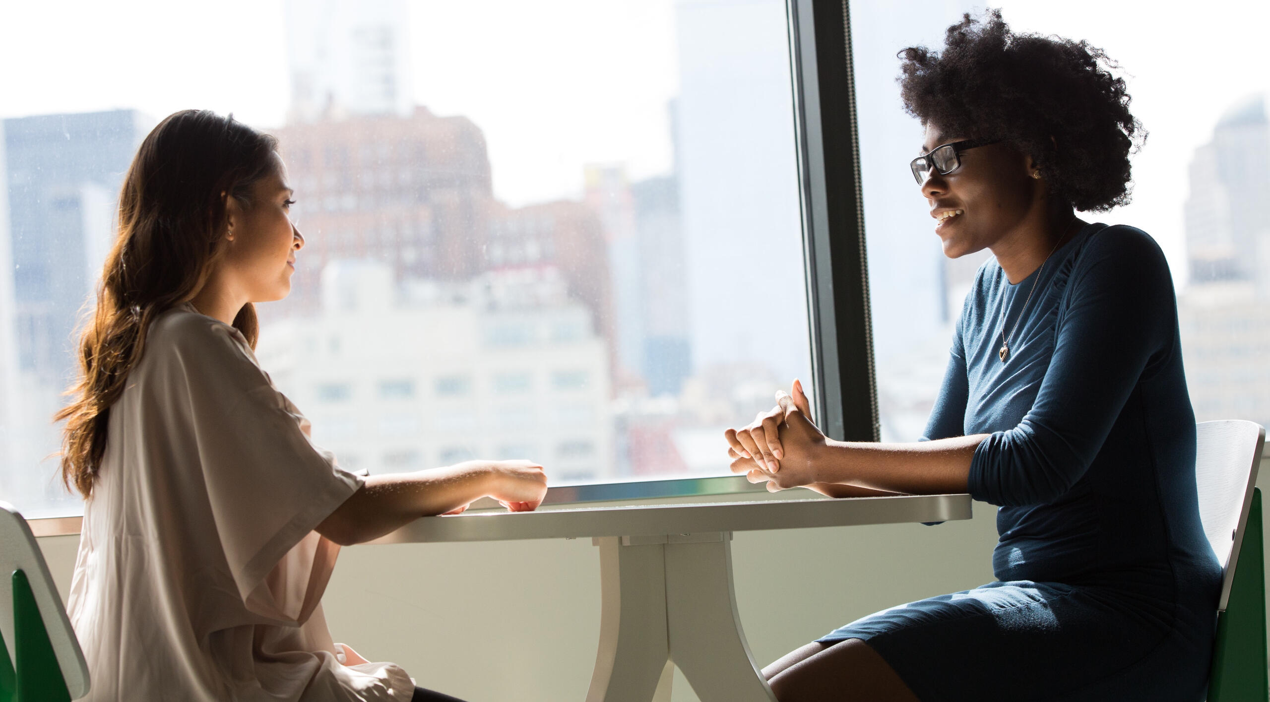 Two women sitting across from each other at a table having a meeting.